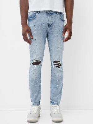 Bershka Jeansy Skinny Z Przetarciami I Plamami Farby Mężczyzna Jasnoniebieski