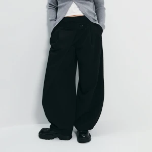 Czarne spodnie baggy z asymetrycznym zapięciem House