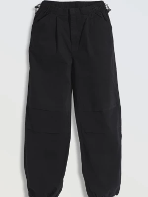 Czarne spodnie typu parachute z zaszewkami na nogawkach