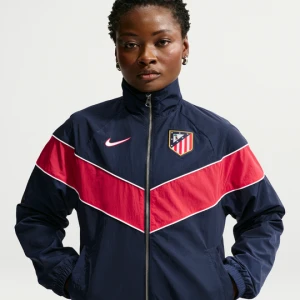 Damska luźna kurtka z tkaniny z zamkiem na całej długości i ochroną przed promieniowaniem UV Atlético Madryt Nike Windrunner (wersja trzecia) - Niebieski