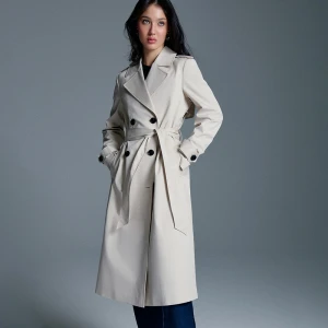 Długi kremowy trencz z paskiem i dwurzędowym zapięciem House