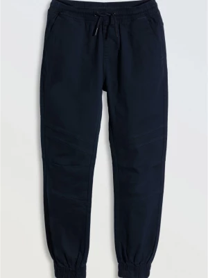 Granatowe spodnie typu joggery z modnymi przeszyciami