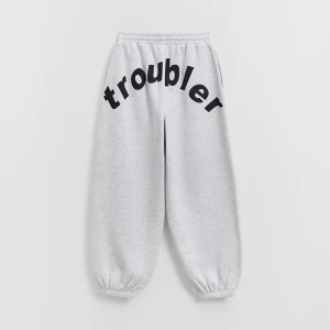 Jasnoszare spodnie dresowe z nadrukiem troubler na tyle House