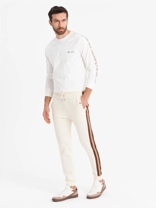 Zdjęcie produktu Dresowe męskie spodnie z lampasami i ściągaczami na nogawkach – kremowe V3 Ombre Clothing kremowy