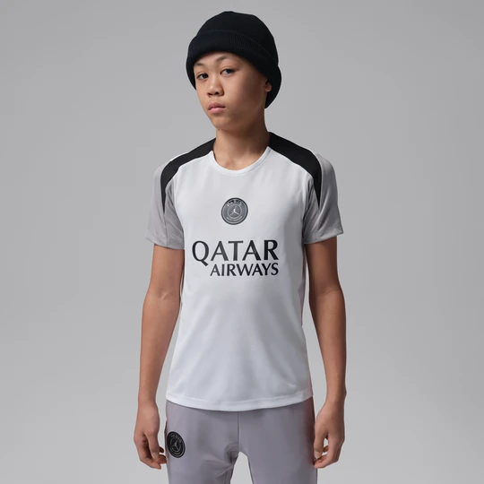 Zdjęcie produktu Dzianinowa koszulka piłkarska z krótkim rękawem dla dużych dzieci Jordan Dri-FIT Paris Saint-Germain Strike (edycja nocna) - Biel
