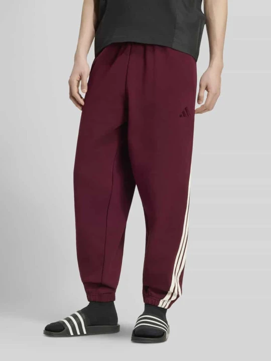 Zdjęcie produktu Spodnie dresowe o kroju regular fit z kieszeniami zapinanymi na zamek błyskawiczny Adidas Ciemnoczerwony