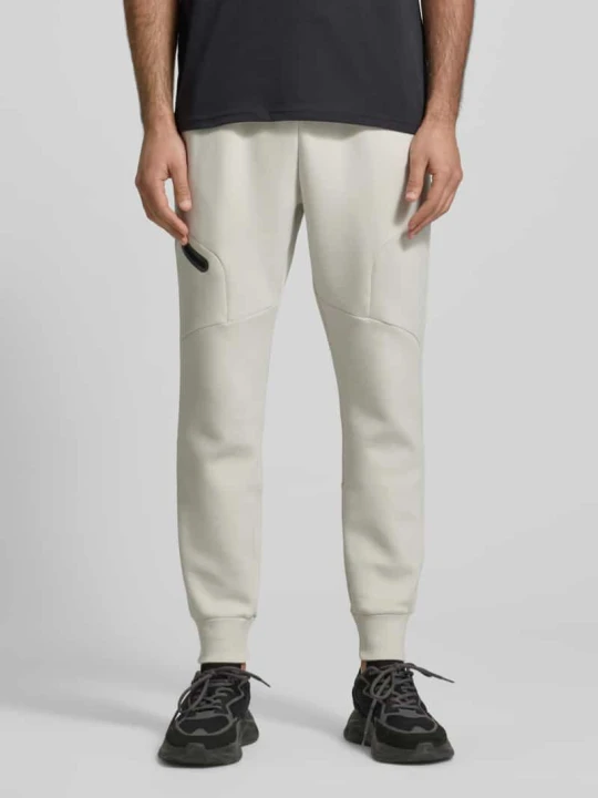 Zdjęcie produktu Spodnie dresowe o kroju regular fit z nadrukiem z logo Model 'Unstoppable' Under Armour Złamany biały
