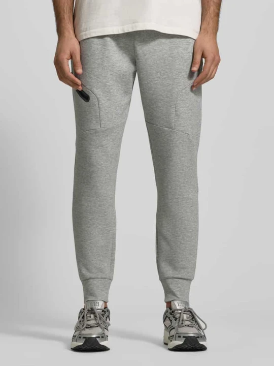 Zdjęcie produktu Spodnie dresowe o kroju regular fit z nadrukiem z logo Model 'Unstoppable' Under Armour Jasnoszary