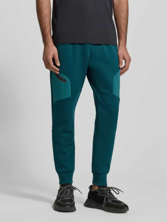 Zdjęcie produktu Spodnie dresowe o kroju regular fit z nadrukiem z logo Model 'Unstoppable' Under Armour Petrol