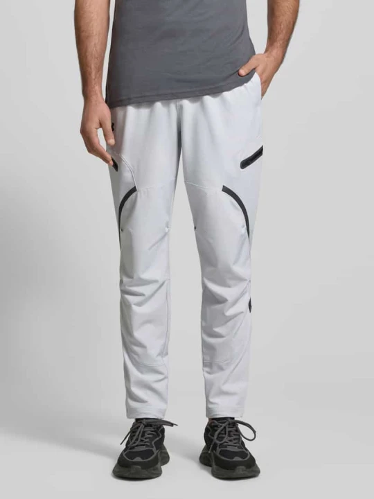 Zdjęcie produktu Spodnie dresowe o kroju regular fit z nadrukiem z logo Model 'Unstoppable' Under Armour Jasnoszary