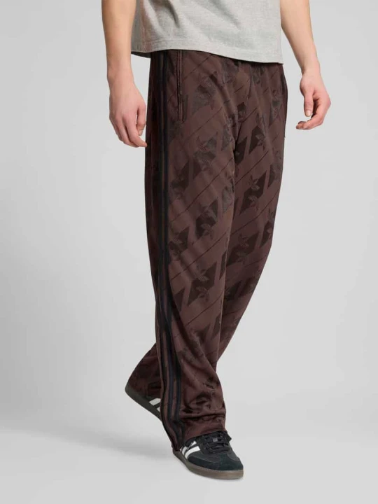 Zdjęcie produktu Spodnie dresowe o kroju relaxed fit z nadrukiem z logo na całej powierzchni adidas Originals Ciemnobrązowy