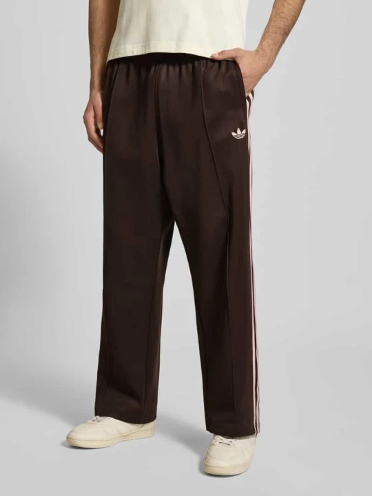 Zdjęcie produktu Spodnie dresowe o kroju regular fit z Wyhaftowane logo Model 'Firebird' adidas Originals Ciemnobrązowy