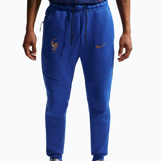 Zdjęcie produktu Spodnie piłkarskie męskie Nike FFF Tech Fleece Joggers game royal/metallic copper Niebieski