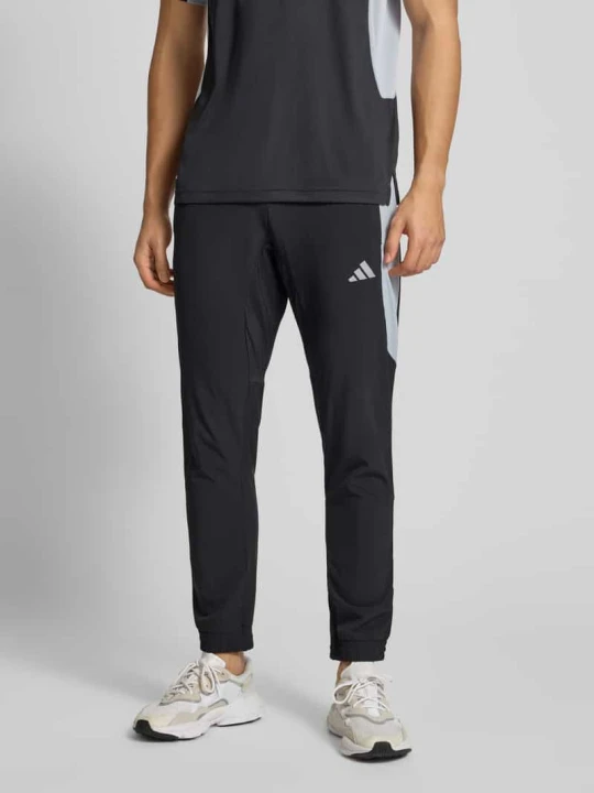 Zdjęcie produktu Spodnie treningowe o kroju slim fit z nadrukiem z logo model ‘Tech’ Adidas Czarny