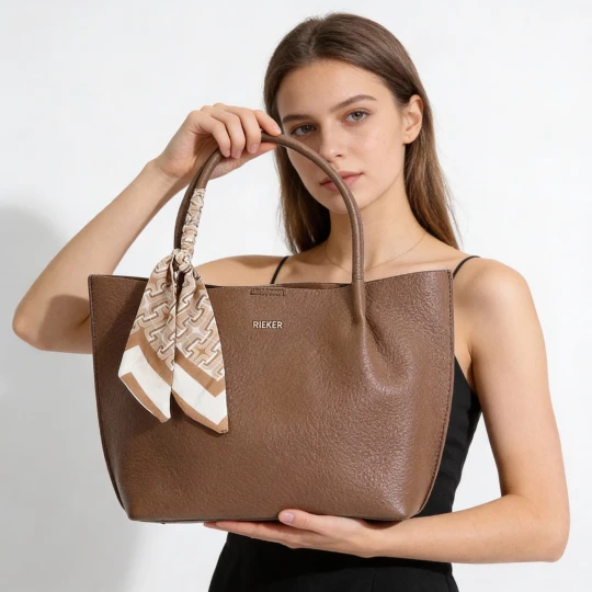 Zdjęcie produktu Torebka damska Rieker, ze skóry ekologicznej o prostej eleganckiej formie z ozdobną apaszką przy uchwycie wygodna do noszenia w dłoni i na ramieniu brązowy