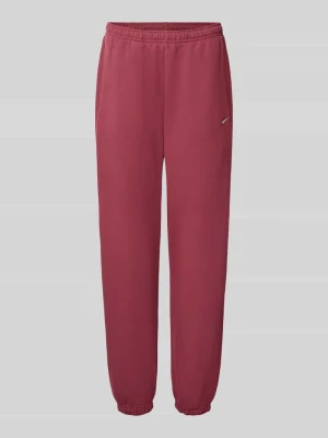 Spodnie dresowe o kroju oversized z mieszanka bawełny Nike Ciemnoczerwony