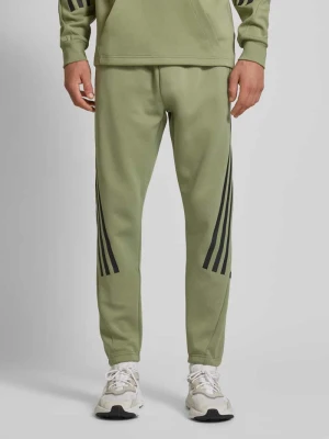 Spodnie dresowe o kroju tapered fit z charakterystycznymi dla marki paskami ADIDAS SPORTSWEAR